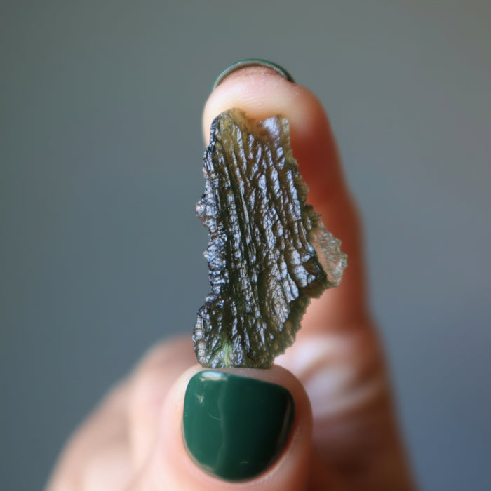 hand holding raw moldavite gemstone
