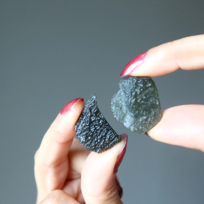 hands holding moldavite stones