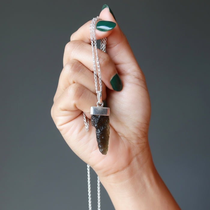hand holding moldavite pendant necklace