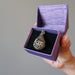 hand holding moldavite locket necklace in purple gift box
