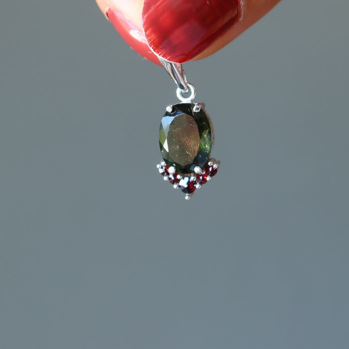 hand holding moldavite garnet pendant