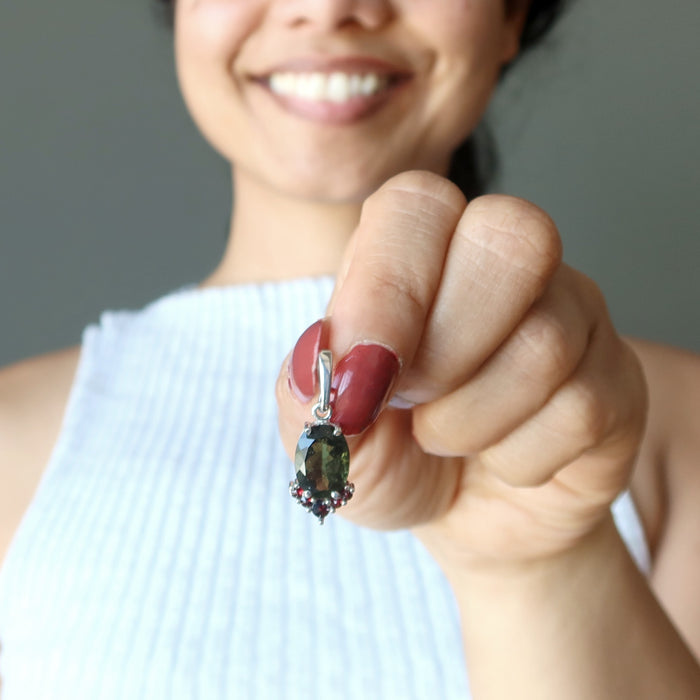 hand holding moldavite garnet pendant to chest