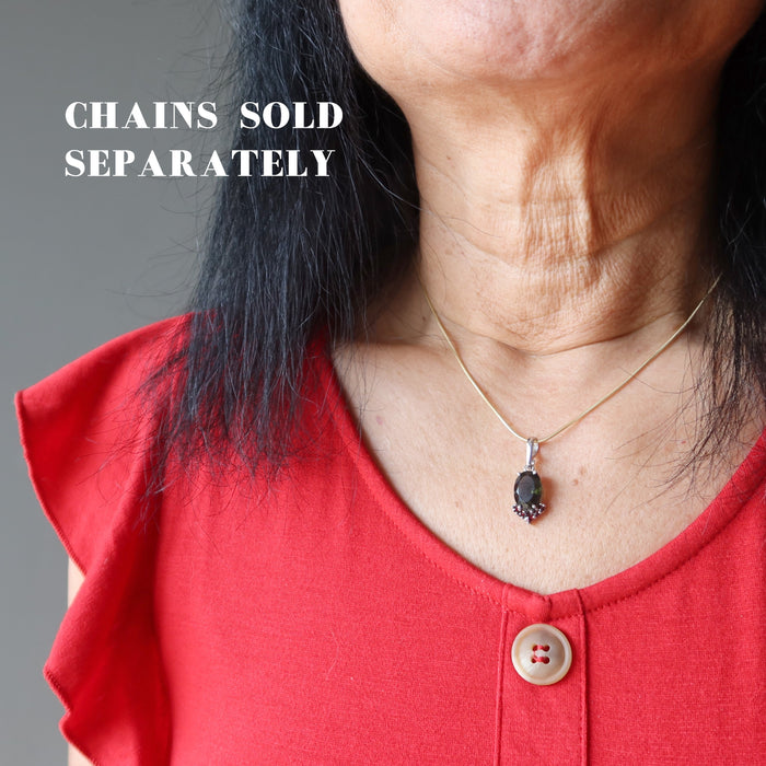 hand holding moldavite garnet pendant on chain, sold separately