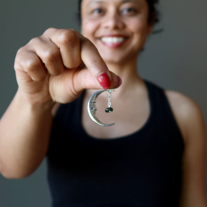 hand holding sterling silver crescent moon with faceted green moldavite pendant
