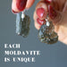 hand holding two moldavite pendants