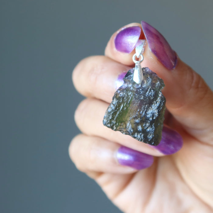 hand holding moldavite pendant