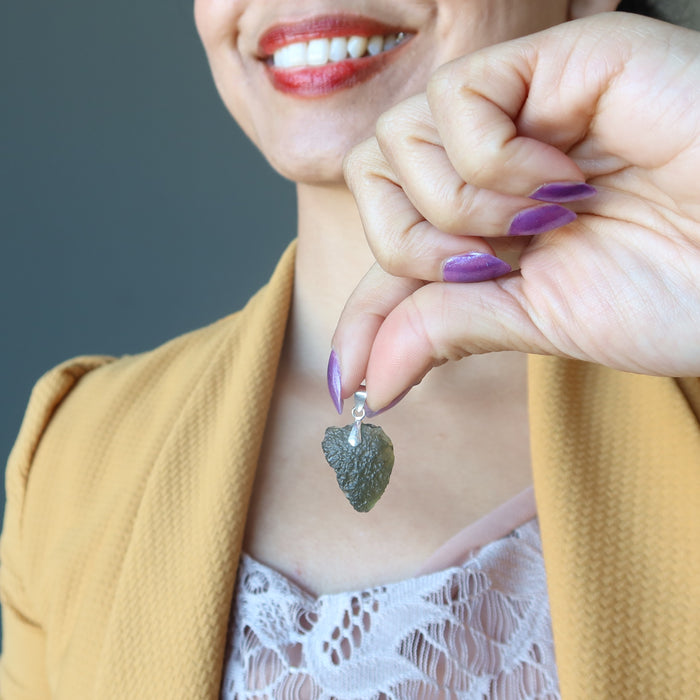 hand holding moldavite pendant to chest
