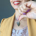 hand holding moldavite pendant to chest