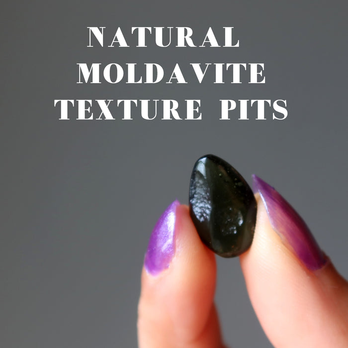 hand holding moldavite with textured pits