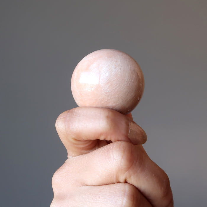 hand holding a peach moonstone sphere