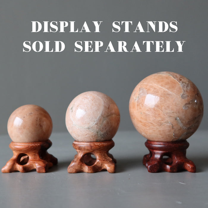 three moonstone spheres on fancy wood display stands, which are sold separately