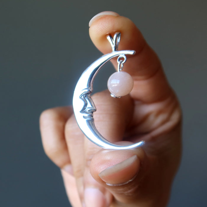 hand holding a sterling silver smiling crescent moon pendant hanging with peach moonstone 