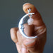 hand holding a sterling silver smiling crescent moon pendant hanging with peach moonstone 
