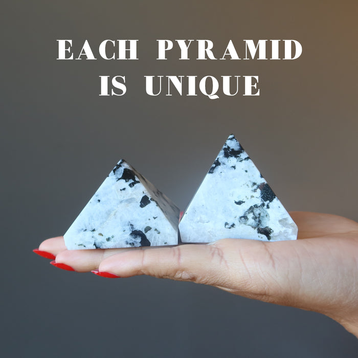 hand holding two tourmalinated moonstone pyramids