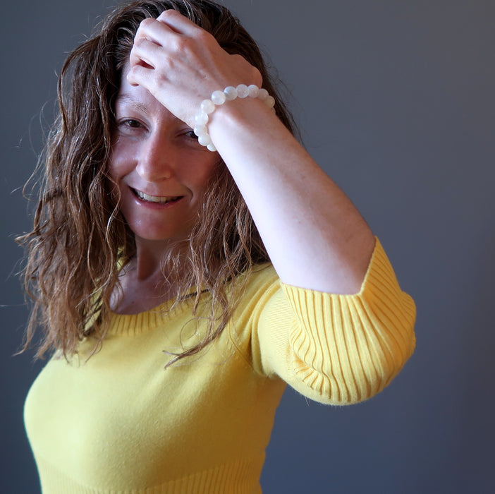 jamie of satin crystals with hand in hair wearing white rainbow moonstone beaded stretch bracelet