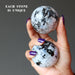 two moonstone tourmaline spheres in hand