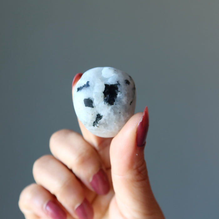 hand holding tumbled moonstone tourmaline stone