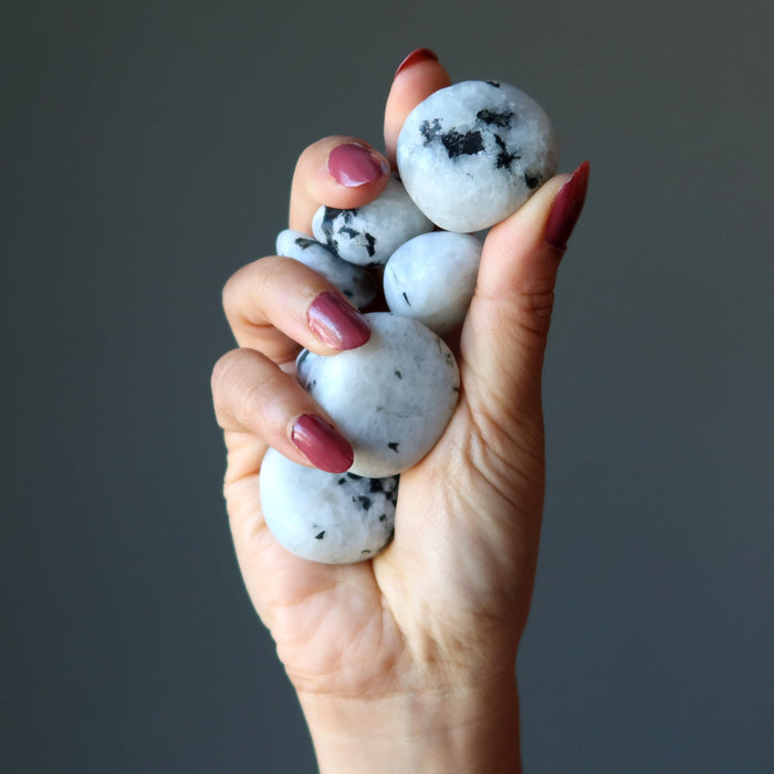 hand holding tumbled moonstone tourmaline stone