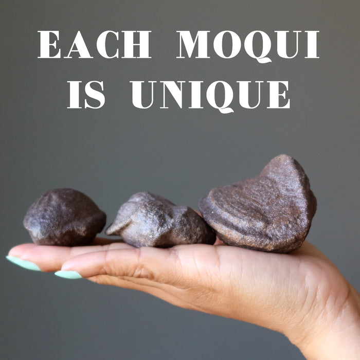 hand holding three natural moqui stones