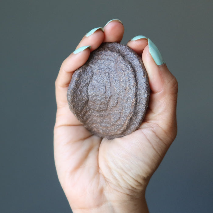 hand holding a natural moqui stone