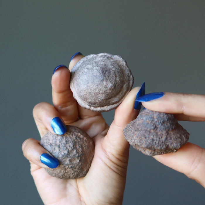 hands holding two male and one female moqui marble stones in varying sizes
