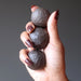 hand holding three brown moqui marble stones