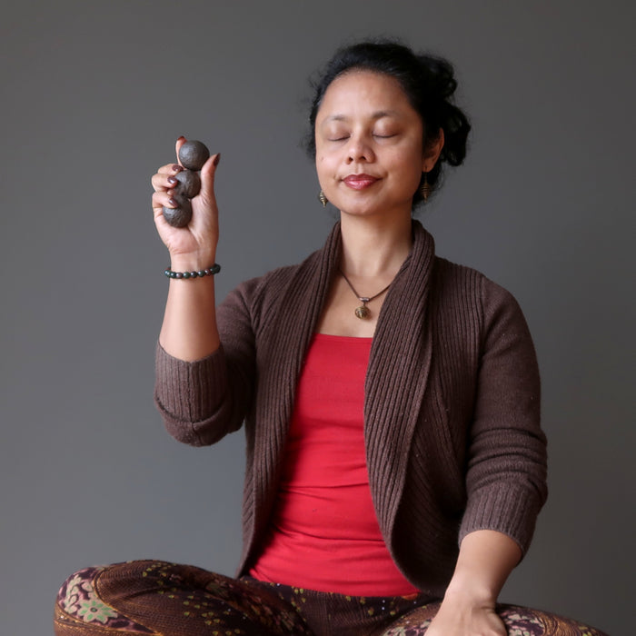 sheila of satin crystals meditating holding three brown moqui marble stones