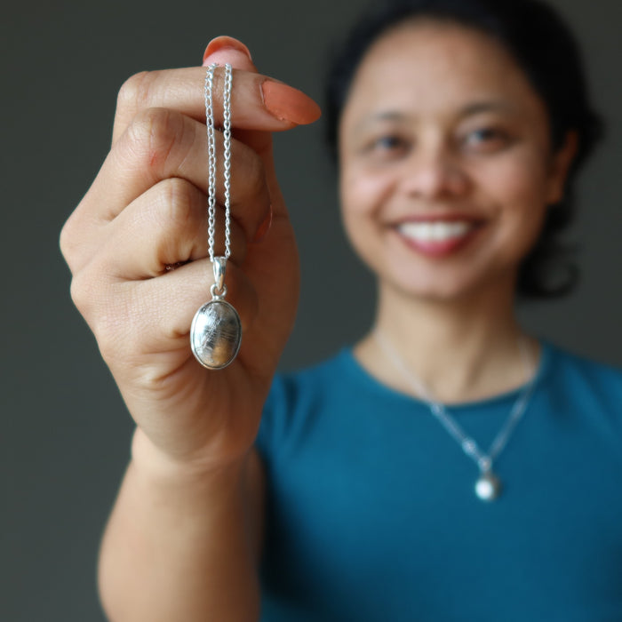 sheila of satin crystals wearing and  holding muonionalusta necklace
