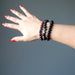 a lady models the obsidian bracelet three piece set on her wrist