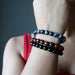 a lady models the obsidian bracelet three piece set on her wrist