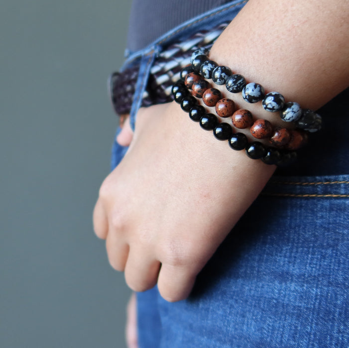 a lady models the black mahogany and snowflake obsidian triple set against her jeans