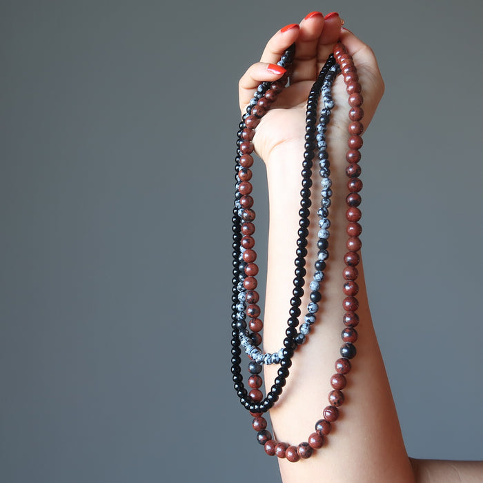 hand holding triple strand obsidian necklace