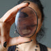 sheila of satin crystals holding up midnight lace obsidian oval stone in front of her face