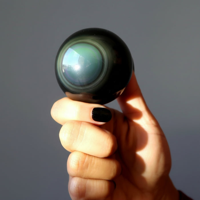 hand holding up a rainbow obsidian sphere