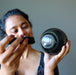 woman using flashlight to shine on rainbow obsidian sphere