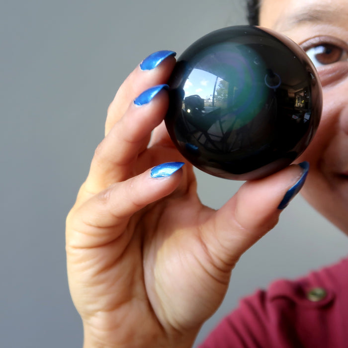 hand holding up a rainbow obsidian sphere