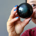 hand holding up a rainbow obsidian sphere