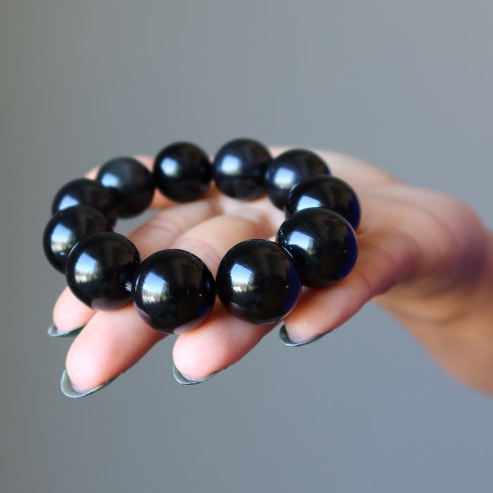 hand holding rainbow obsidian beaded stretch bracelet