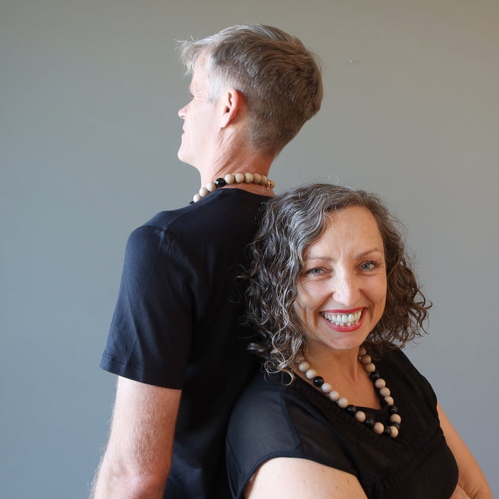 man and woman back to back wearing rainbow obsidian necklaces