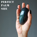 hand holding rainbow obsidian palm stone