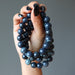 hand holding 3  round spiderweb obsidian stretch bracelet