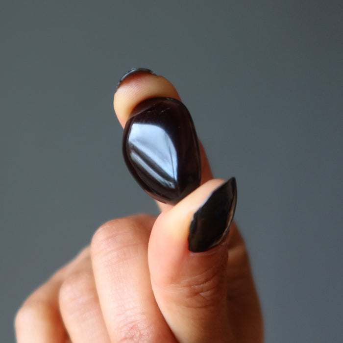 hand holding one obsidian tumbled stone