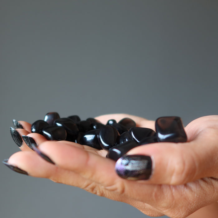 hand holding 43 black obsidian tumbled stones
