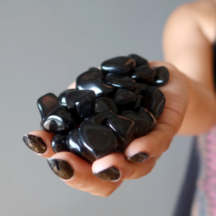 hand holding 43 black obsidian tumbled stones