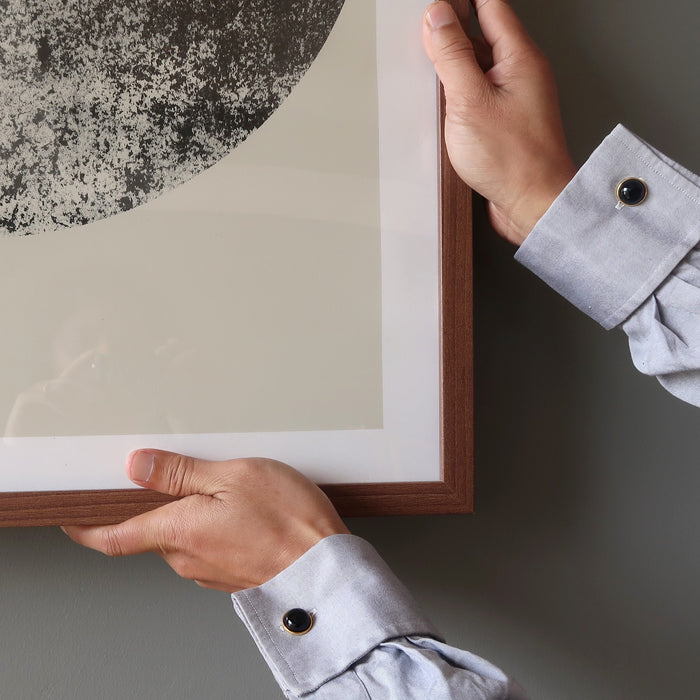 hand adjusting a frame wearing black onyx cufflinks