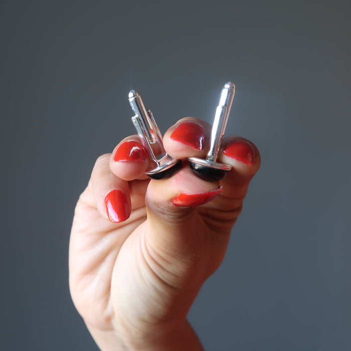 hands holding up black onyx cufflinks