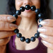hands holding a matte and polished glossy beaded round black onyx stretch bracelet