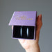 hand holding black onyx oval earrings in purple satin crystals gift box