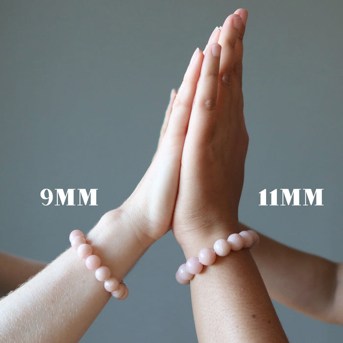 two people wearing pink opal bracelets on their wrists, one labeled at 9 and the other at 11 millimeters