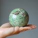 hand holding green opal sphere 